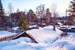 Siberian village at winter covered by snow at evening time