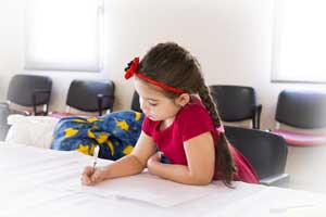 English to Haitian Creole Translation - Young Girl working at table