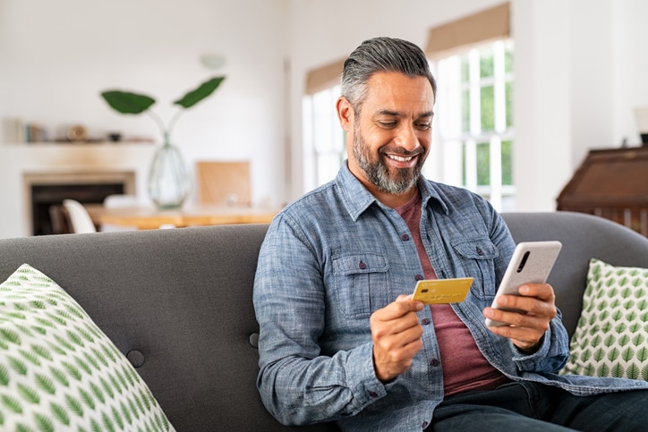 Mixed race man paying online on mobile phone retail banking website localization
